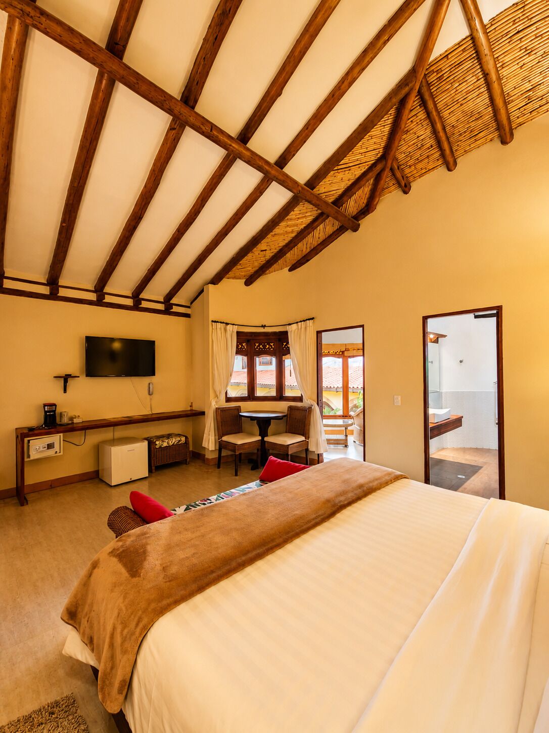 A bedroom with a bed, a desk, a TV, and a balcony.