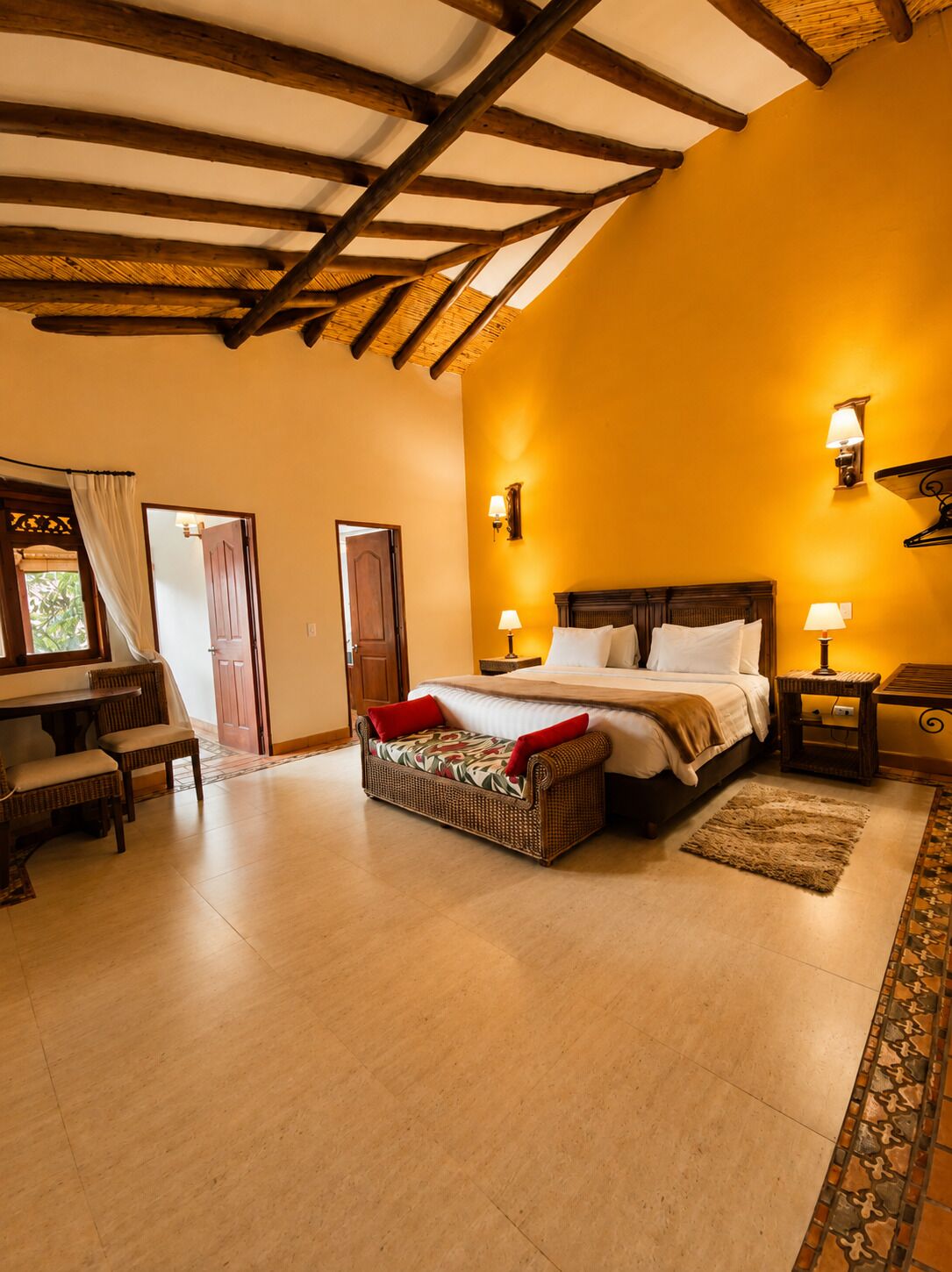 A bedroom with a bed, bedside tables, a sofa, and a dining area with chairs.