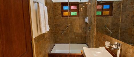 A modern bathroom with a glass-enclosed shower, a freestanding bathtub, and a vanity with a sink.