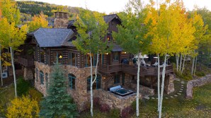 Une cabane en rondins à plusieurs niveaux, avec des murs en pierre et un jacuzzi.