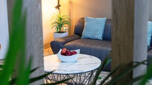 A cozy living area with a sofa, a small table, and a potted plant. - Palmetto Hotel Business La Perla (Callao)
