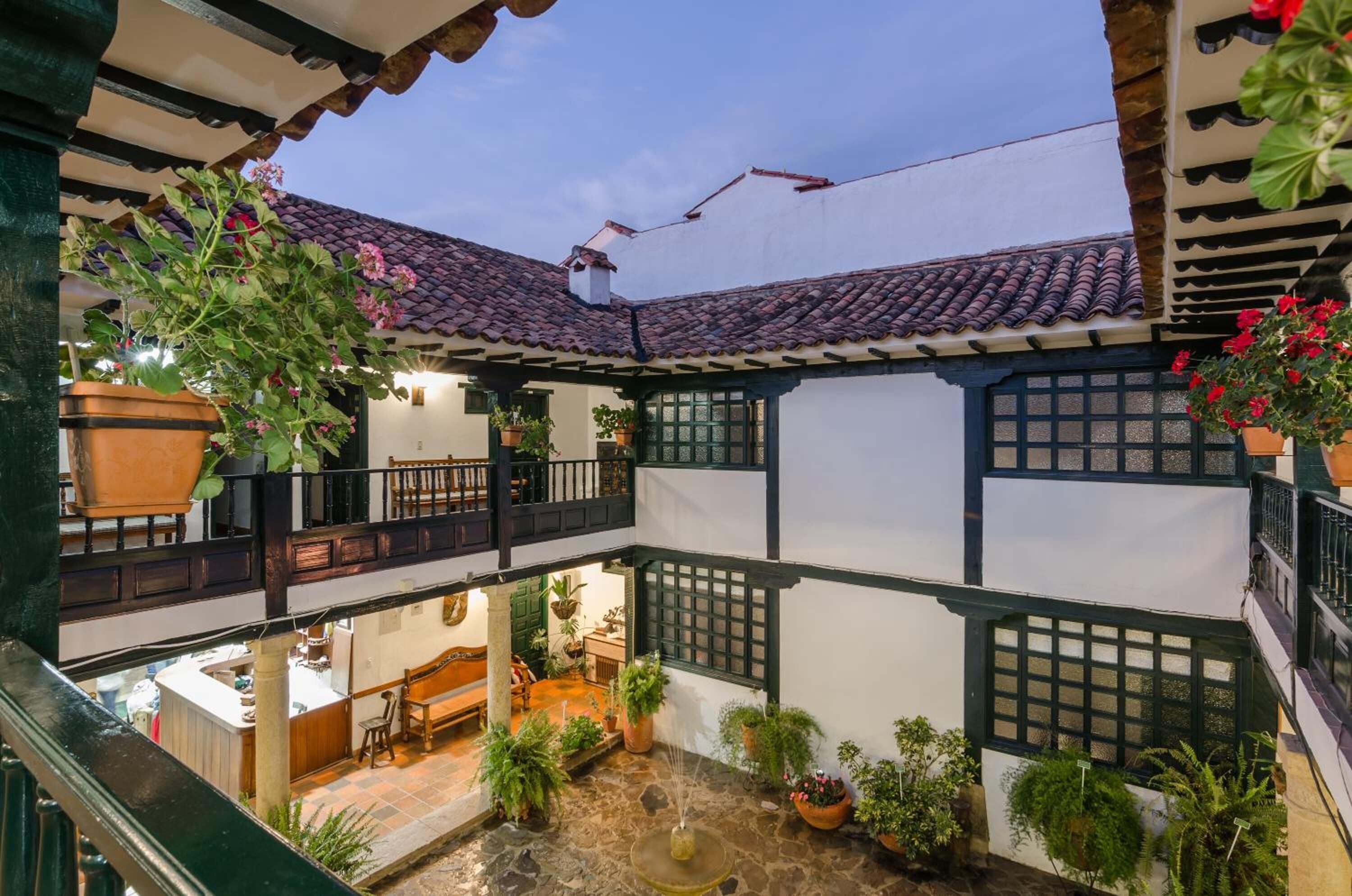 A traditional courtyard with a tiled roof, potted plants, and a stone fountain.