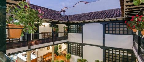 A traditional courtyard with a tiled roof, potted plants, and a stone fountain.