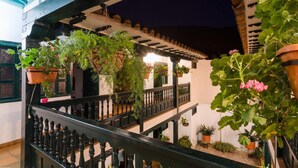 A courtyard with hanging planters and a balcony railing. - Hotel Antonio Nariño (Villa de Leyva)