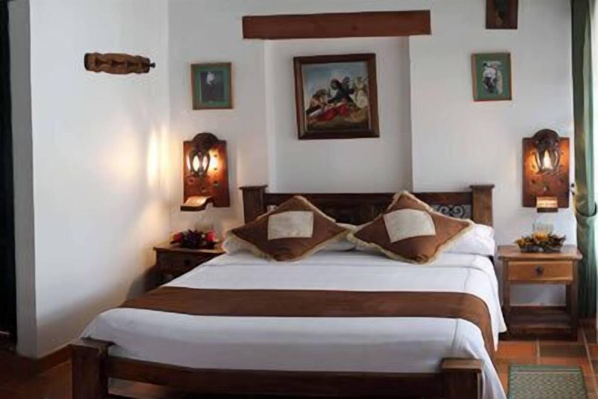 Una habitación con dos literas, un cabecero de madera, una mesita de noche con lámpara y una estantería en la pared con objetos decorativos.