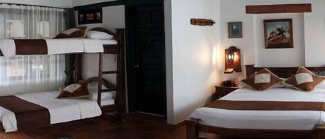 A room with two bunk beds, a wooden headboard, a nightstand with a lamp, and a wall-mounted shelf with decorative items.
