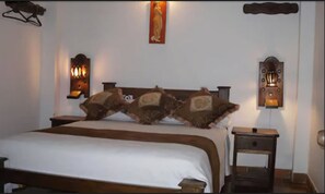 A bed with a wooden headboard, two wall-mounted lamps, and a nightstand with a drawer.
