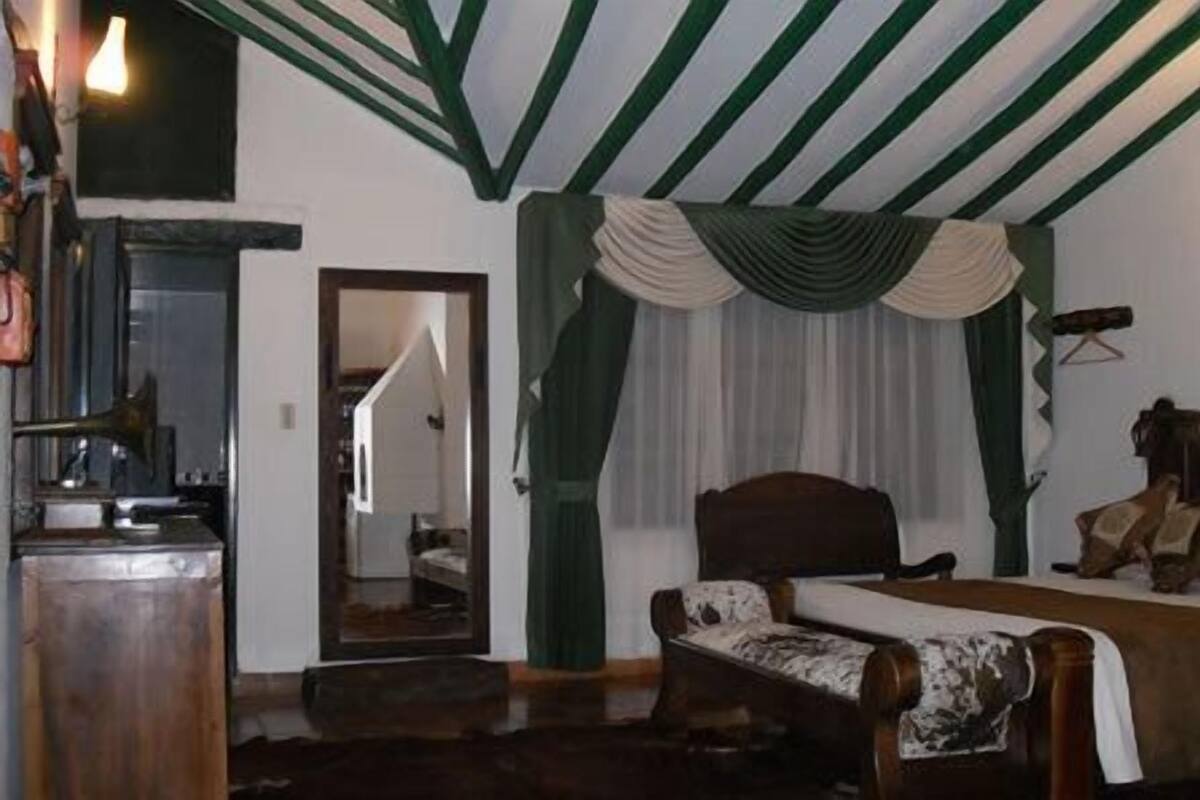 Un dormitorio con cama, una silla, un escritorio y un espejo.