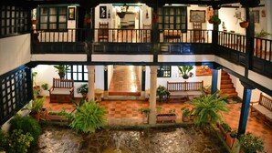 A courtyard with a central fountain, potted plants, and a checkered floor. - Hotel Antonio Nariño (Villa de Leyva)