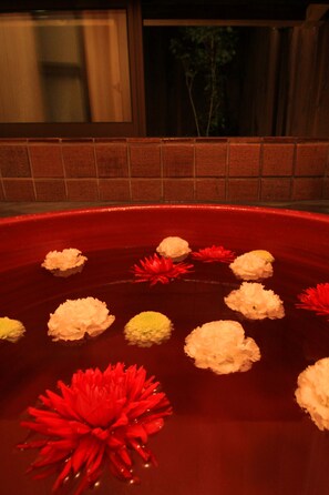 A red bathtub with water lilies and a red flower.