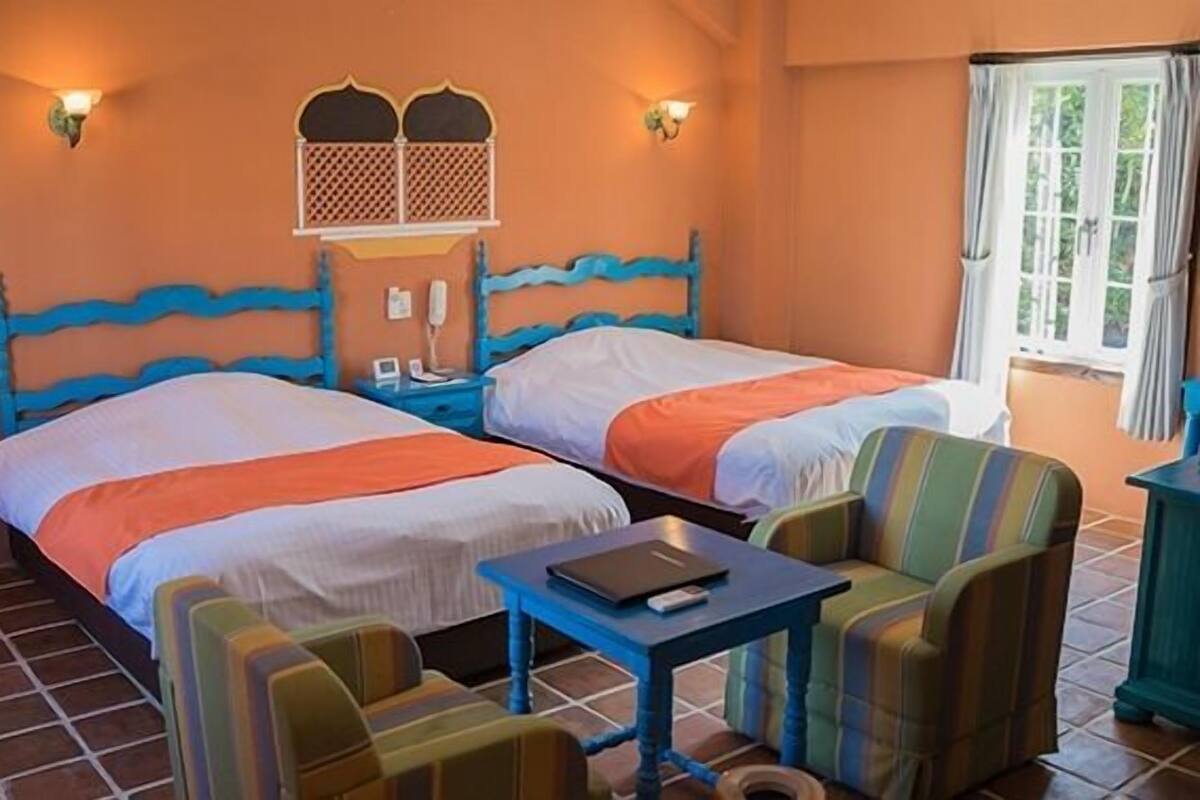 Una habitación de hotel con dos camas, una mesita y una silla.