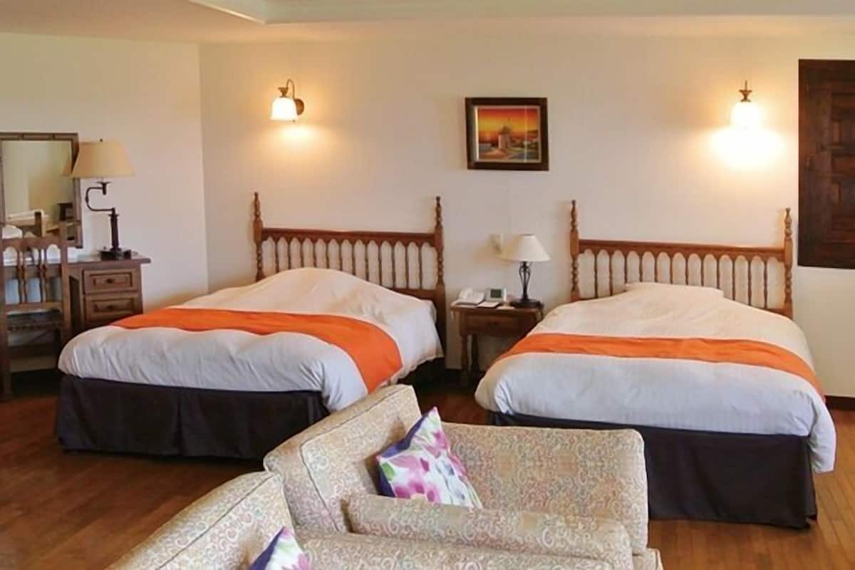 Una habitación de hotel con dos camas, un escritorio, una silla y una mesita de noche.