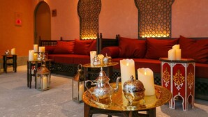 A cozy lounge area with a sofa, decorative lamps, and a table with ornate metalware. - Shima Mediterranean Village (Shima)