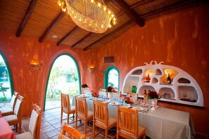 Un comedor con una mesa dispuesta para cuatro personas, sillas de madera y una lámpara decorativa en el techo.