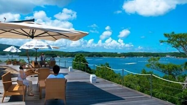 A wooden deck with outdoor seating and umbrellas overlooking a body of water. - Shima Mediterranean Village (Shima)