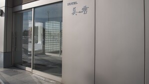 A hotel entrance with a glass door and a sign indicating the name in both English and another language. - Hotel Miyuki (Wakkanai)