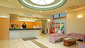 A hotel reception area with a reception desk, a Coca-Cola refrigerator, a vending machine, and a seating area with a coffee table. - Hotel Miyuki (Wakkanai)