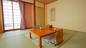 A traditional Japanese room with tatami flooring, a low wooden table, a cushioned bench, sliding doors, and a large window with a view. - Hotel Miyuki (Wakkanai)