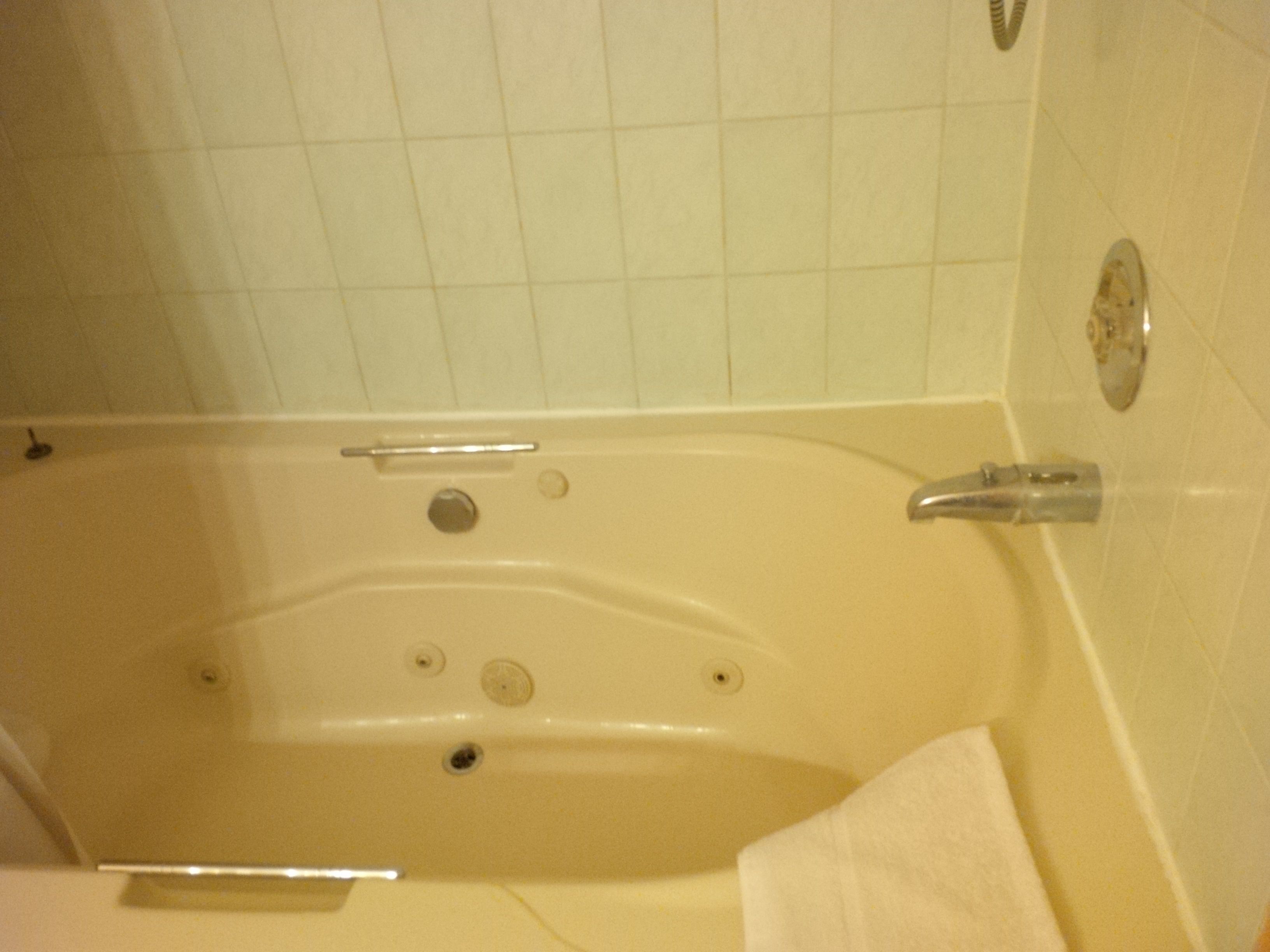 A bathtub with a handheld showerhead, a built-in drain, and a faucet.