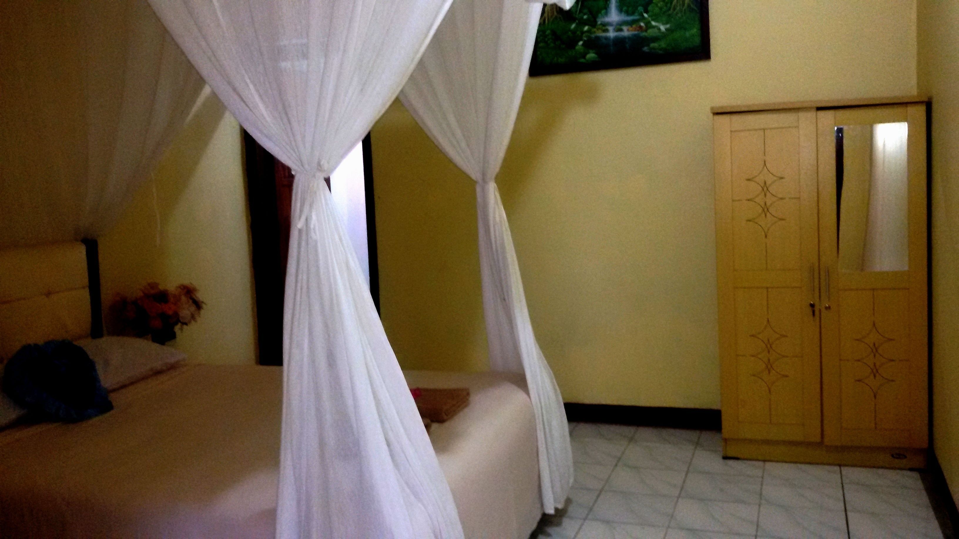A bedroom with a bed, a wardrobe, and a painting on the wall.