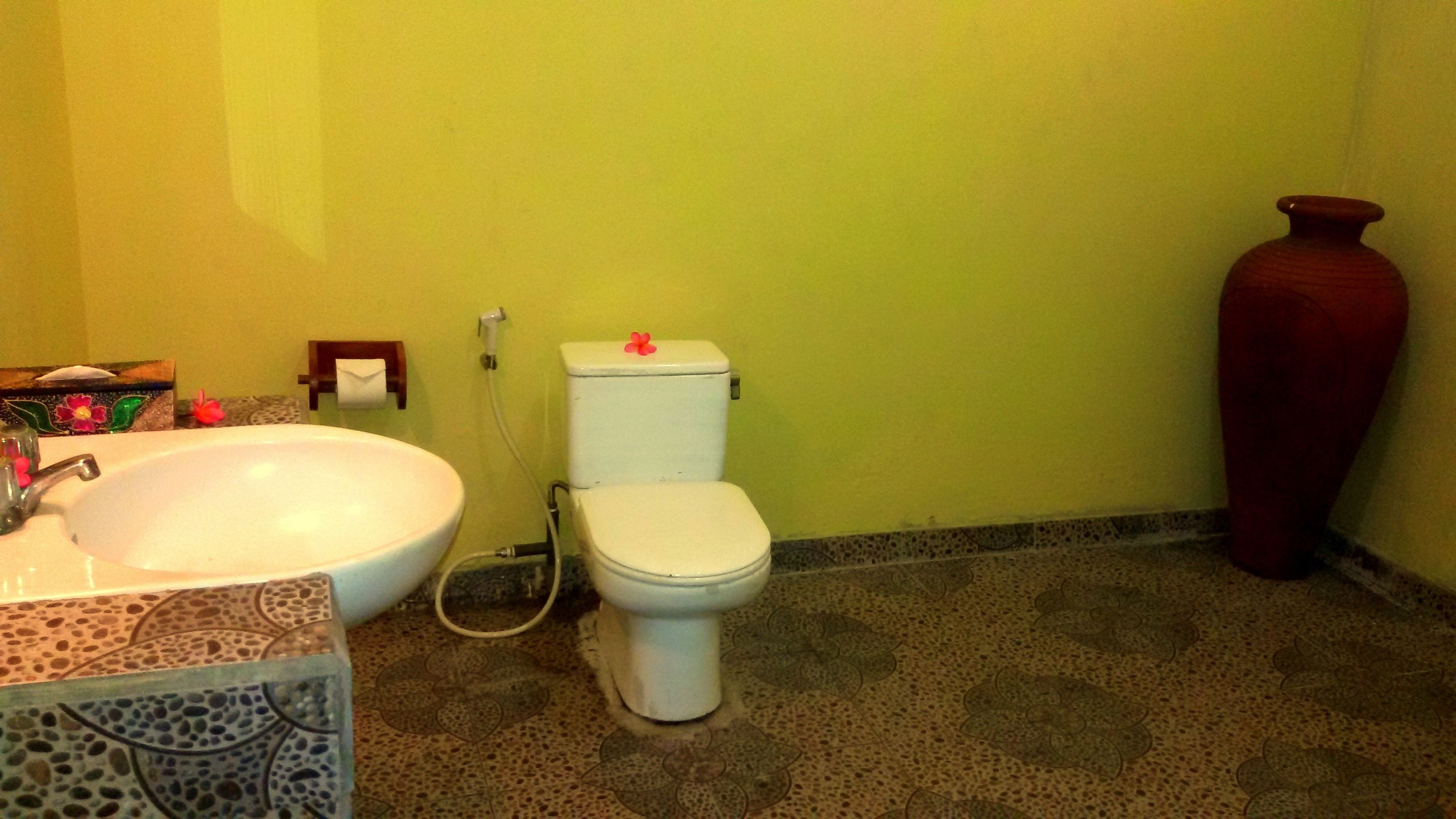 A bathroom with a white sink, toilet, and a large red vase.