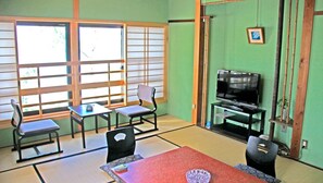 A traditional Japanese room with tatami flooring, a low table, and a television. - Nisshokan (Ise)