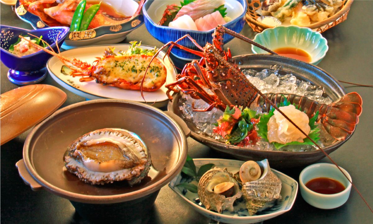A variety of seafood dishes including lobster, oysters, and fish, served on a table with multiple bowls and plates.