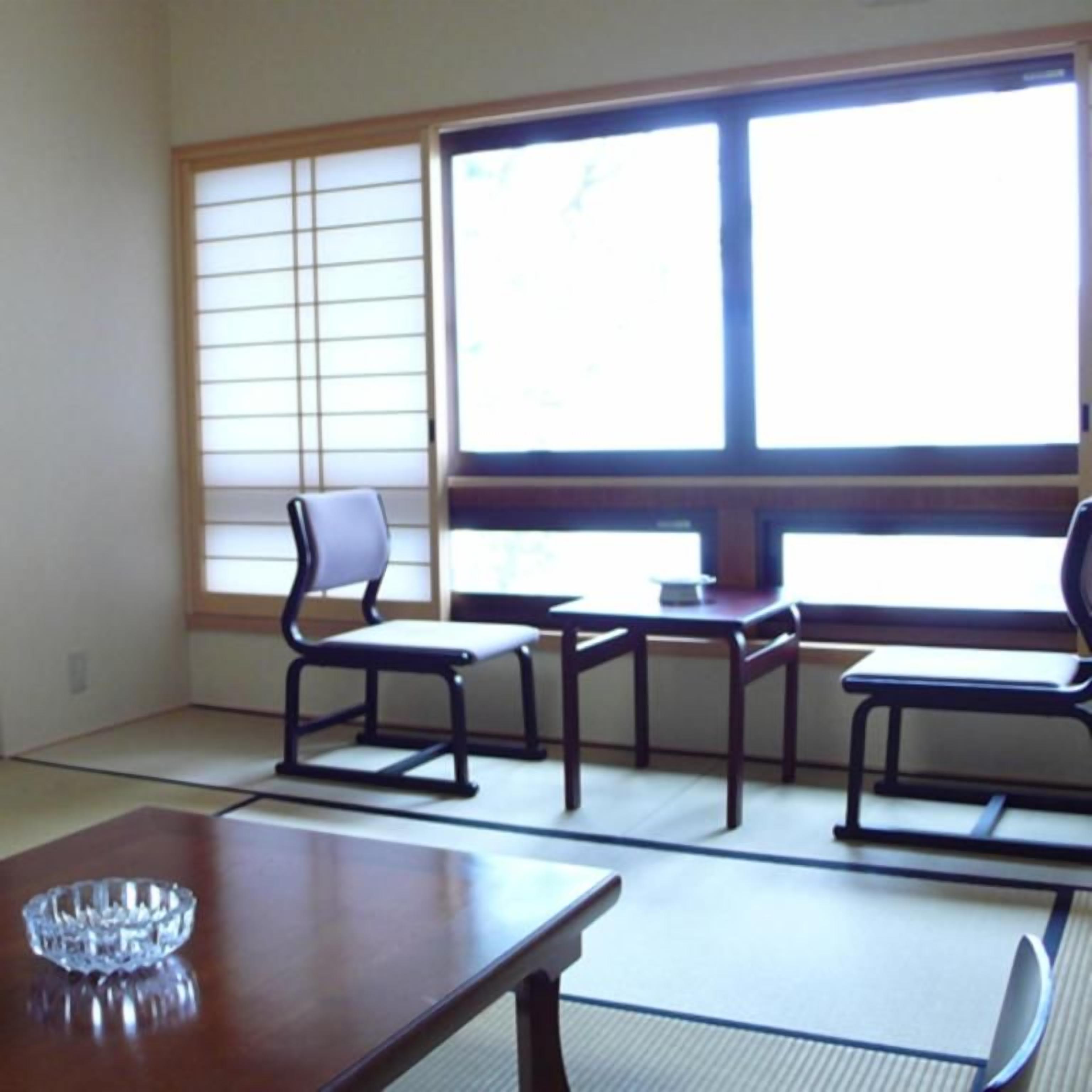 A traditional Japanese room with tatami flooring, a low table with a glass bowl, and a sliding door.