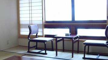 A traditional Japanese room with tatami flooring, a low table with a glass bowl, and a sliding door.