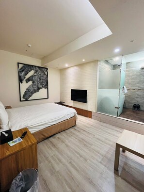A modern hotel room with a bed, a flat-screen TV mounted on the wall, a glass shower enclosure, and a wooden nightstand with a remote control. - Walker Hotel Ximen (Taipei)