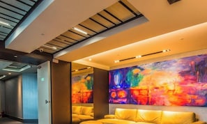 A modern hotel lobby with a large abstract painting, a reception desk, and a seating area with yellow sofas. - Walker Hotel Ximen (Taipei)