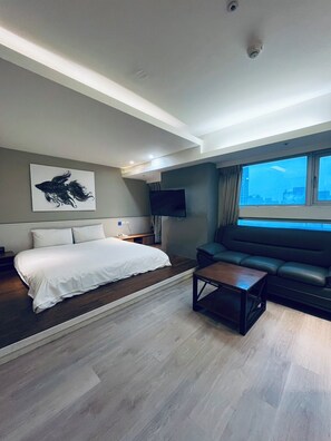 A modern hotel room with a bed, a sofa, a coffee table, and a television. - Walker Hotel Ximen (Taipei)