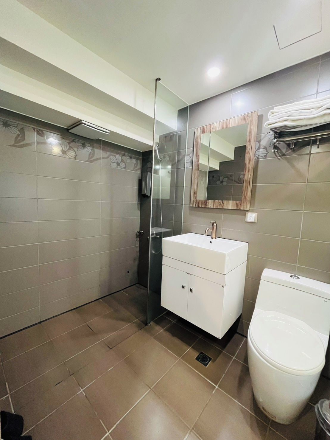 A bathroom with a glass shower enclosure, a white sink, and a toilet.