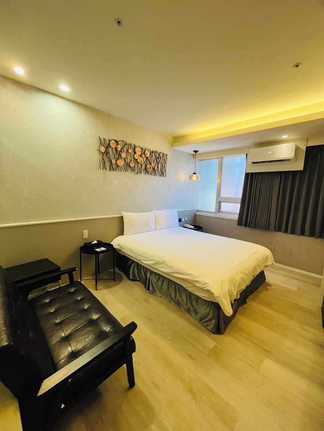 A hotel room with a bed, bedside table, and a bench.