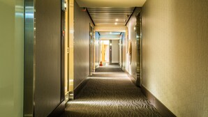 A hotel hallway with a patterned carpet, doors on both sides, and a ceiling with recessed lighting. - Walker Hotel Ximen (Taipei)