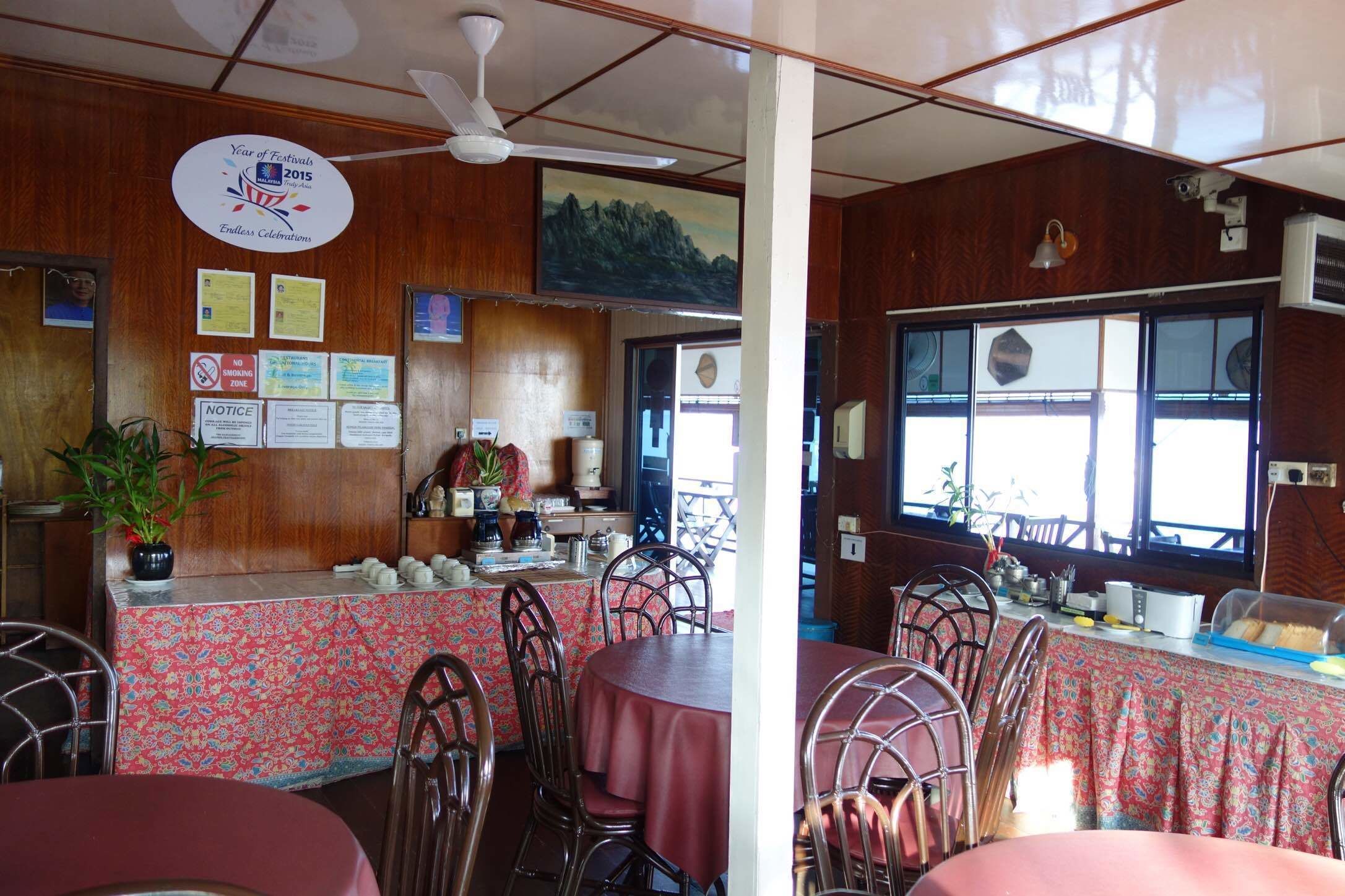 A restaurant with wooden walls, a ceiling fan, and a view of the mountains through the windows.