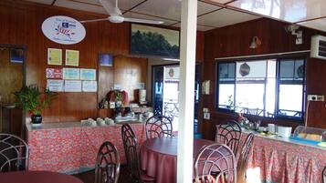 A restaurant with wooden walls, a ceiling fan, and a view of the mountains through the windows.
