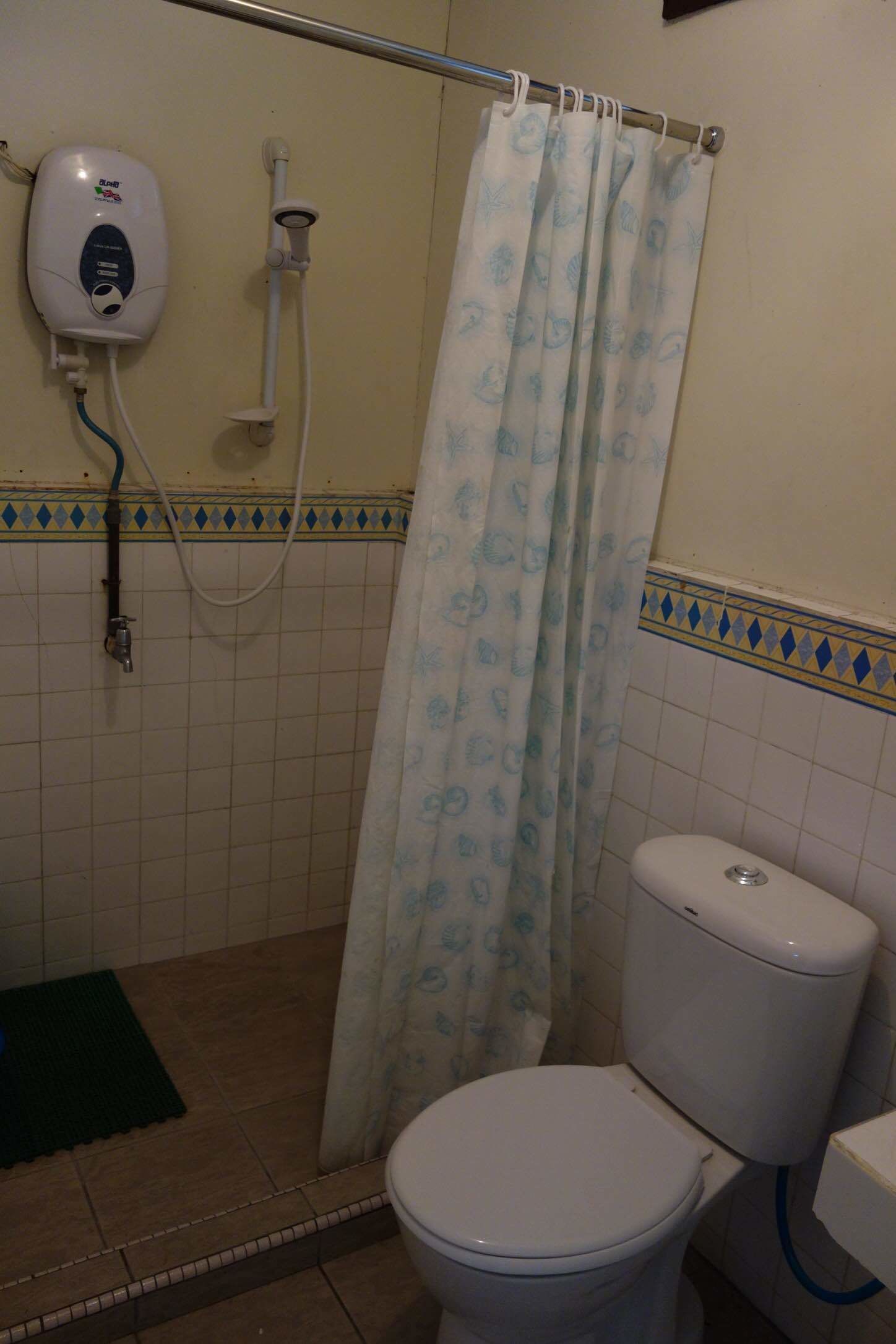 A bathroom with a toilet, a shower with a curtain, and a hand dryer.