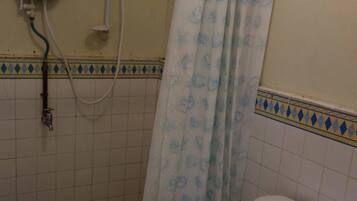 A bathroom with a toilet, a shower with a curtain, and a hand dryer.