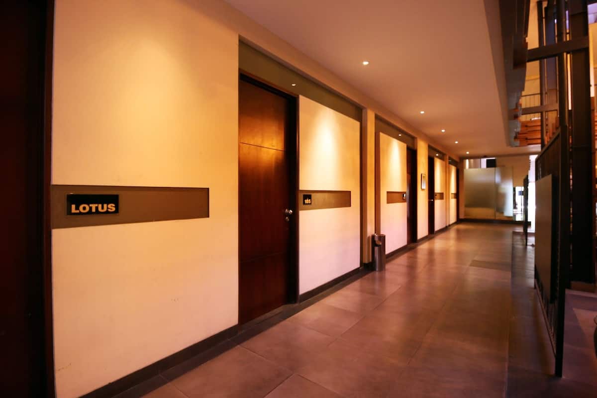 Un pasillo de hotel con puertas que dicen "LOTUS" y un cubo de basura.