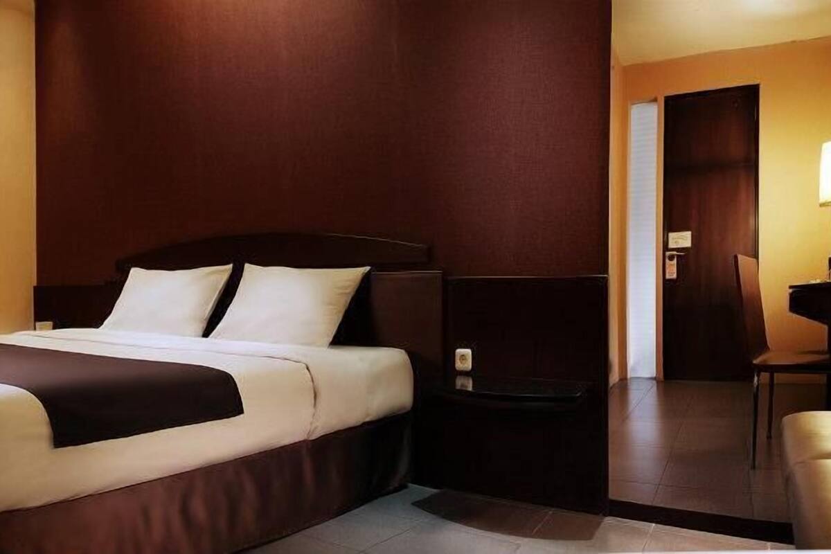 Una habitación de hotel con una cama, una mesita de noche, una silla y un escritorio.
