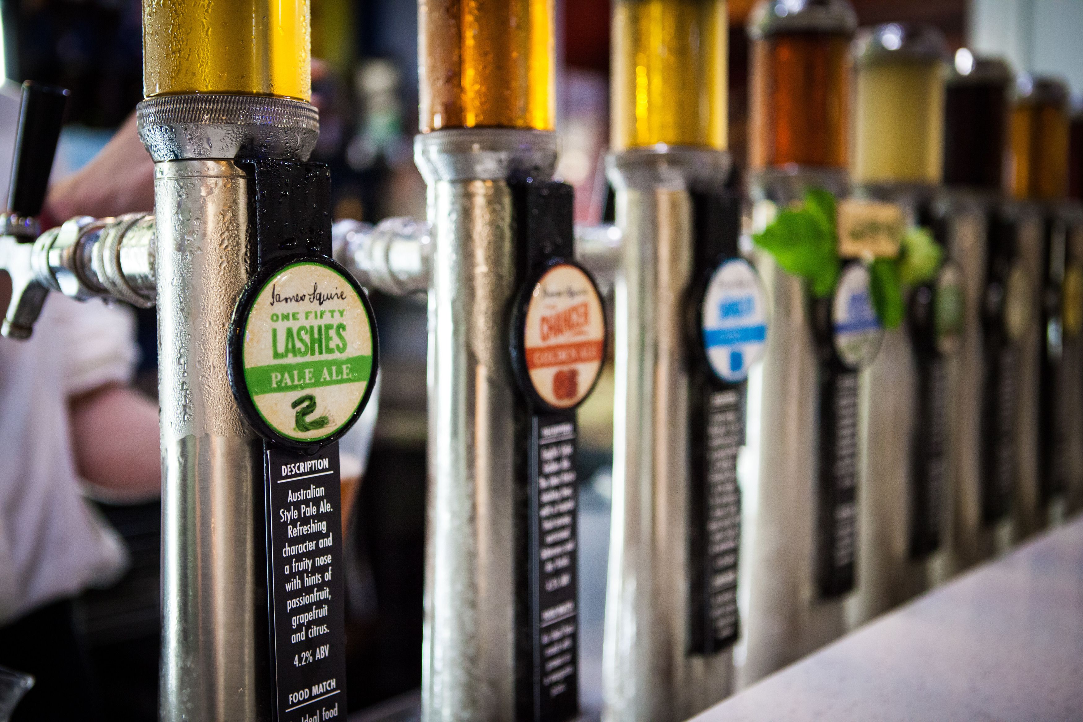 A row of beer taps with labels, including one for James Aquila Pale Ale.