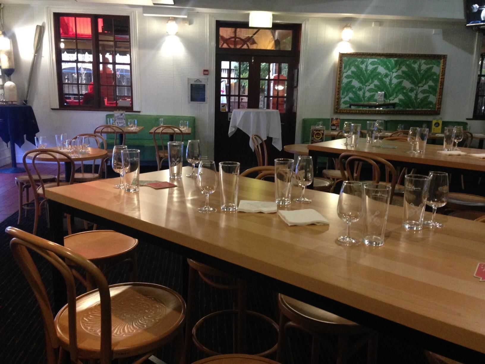 Un restaurant avec des tables et des chaises en bois, dont certaines sont ornées de verres à vin vides.