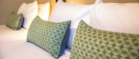 Cama bem arrumada com almofadas de padrão branco e verde.