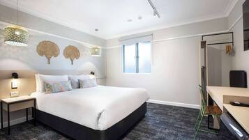 Un dormitorio moderno con una cama grande, mesitas de noche, un escritorio y un espejo.