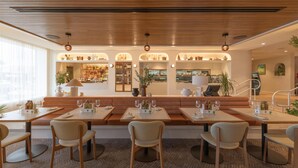 A modern restaurant with wooden ceiling, multiple seating areas, and a view of the cityscape. - Nightcap at Manly Hotel (Manly)