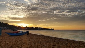 A beach with a boat, a sign, and a sunset. - Sandaya's Place (Unawatuna)