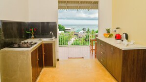 A kitchen with a view of the sea, a gas stove, a sink, and a small balcony with a railing. - Sandaya's Place (Unawatuna)
