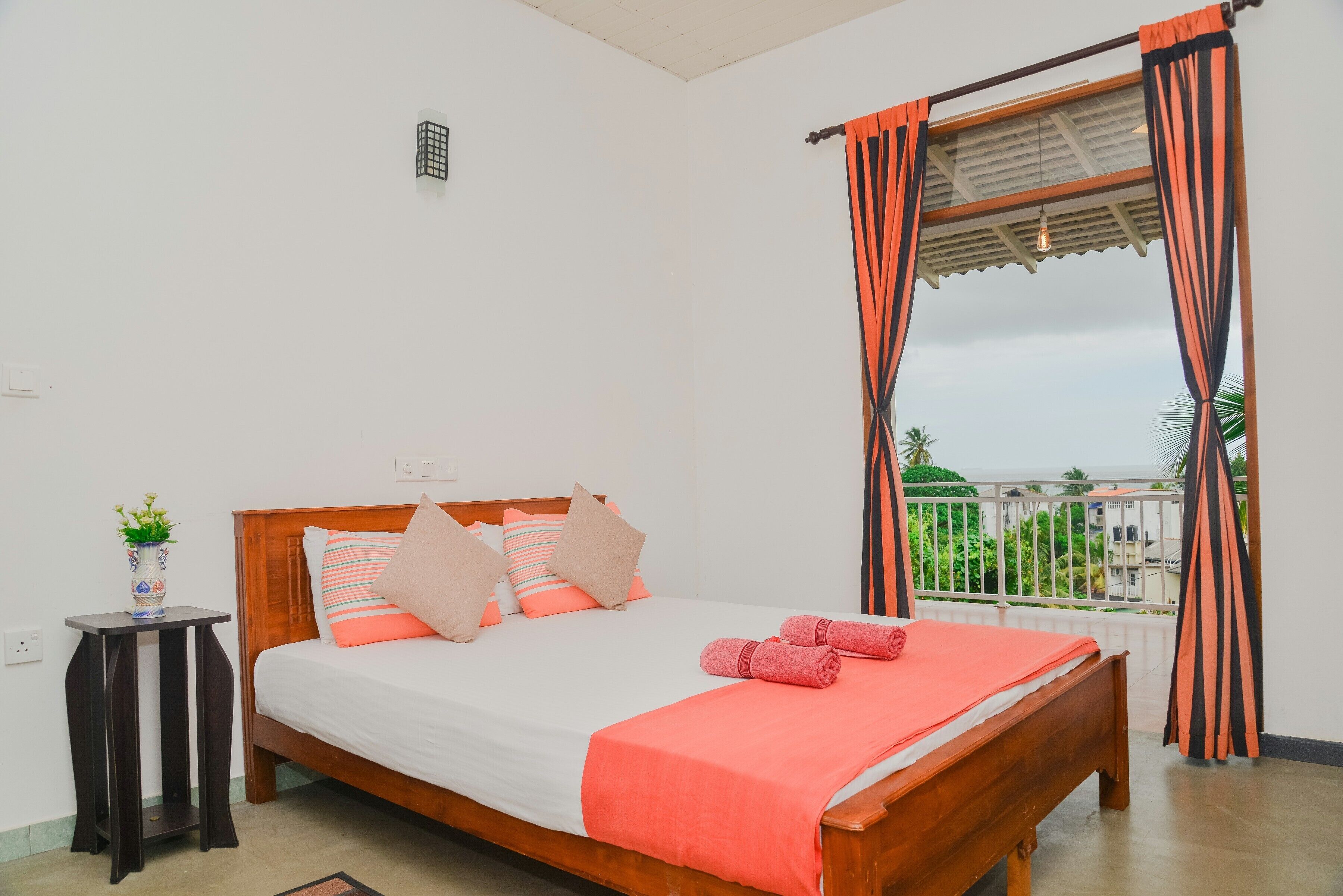Ein Schlafzimmer mit einem hölzernen Bett, weißer Bettwäsche und Blick auf Grün.