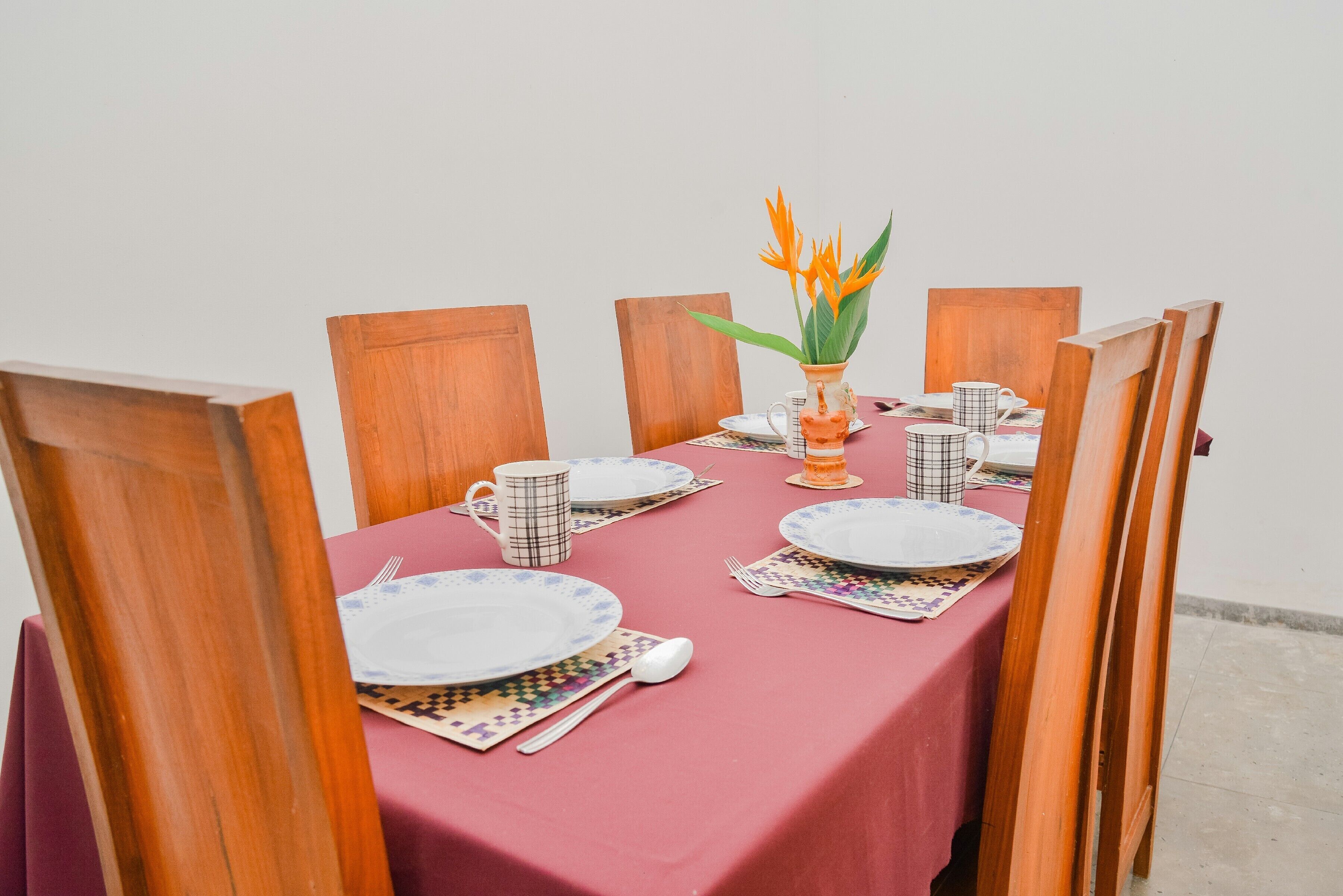 A dining table set with plates, cutlery, and a vase with flowers.